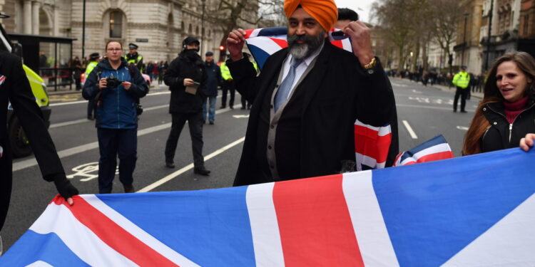LONDON, ENGLAND - JANUARY 31: Pro Brexit supporters wave Union Jack flags at Parliament Square as people prepare for Brexit on January 31, 2020 in London, United Kingdom. At 11.00pm on Friday 31st January the UK and Northern Ireland will exit the European Union 188 weeks after the referendum on June 23rd 2016.  (Photo by Jeff J Mitchell/Getty Images)